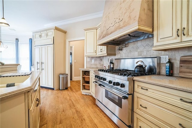 kitchen with custom exhaust hood, decorative light fixtures, ornamental molding, range with two ovens, and cream cabinetry