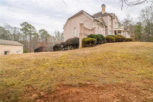 view of side of home with a lawn and a balcony