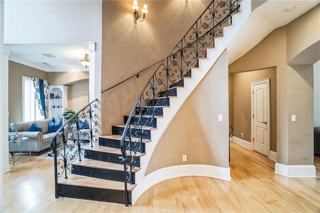 stairs featuring hardwood / wood-style floors, a towering ceiling, and ornamental molding