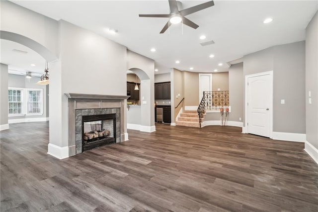 unfurnished living room with dark wood-type flooring, a multi sided fireplace, and ceiling fan