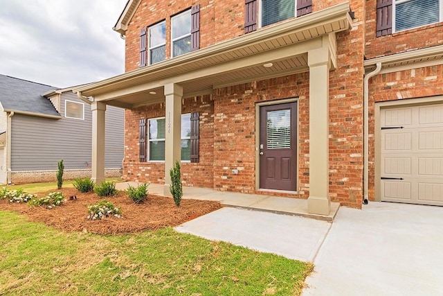 doorway to property with a garage, covered porch, and brick siding