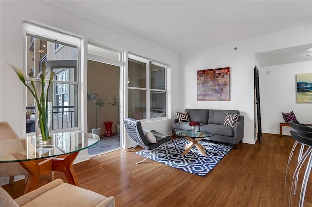 living room with dark wood-type flooring, crown molding, and a healthy amount of sunlight