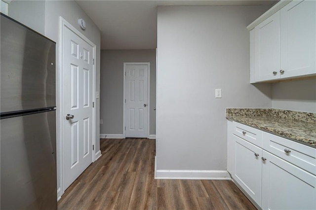 kitchen featuring white cabinetry, dark hardwood / wood-style flooring, stainless steel fridge, and light stone countertops