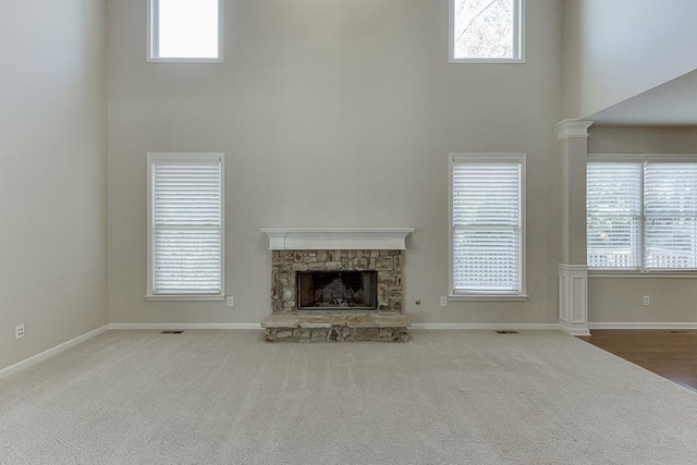 unfurnished living room featuring a wealth of natural light, a fireplace, and a towering ceiling