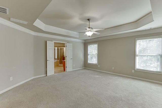 carpeted empty room with a raised ceiling, crown molding, and ceiling fan