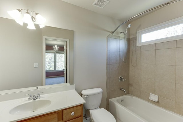 full bathroom featuring tiled shower / bath, vanity, toilet, and plenty of natural light