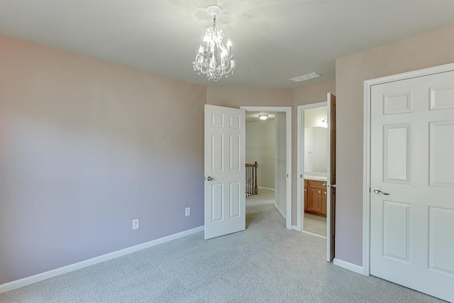 unfurnished bedroom with ensuite bathroom, light colored carpet, and a notable chandelier