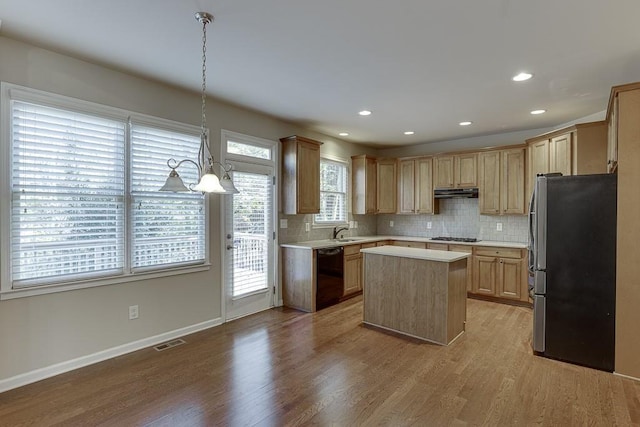 kitchen featuring stainless steel refrigerator, dishwasher, a center island, light hardwood / wood-style flooring, and pendant lighting