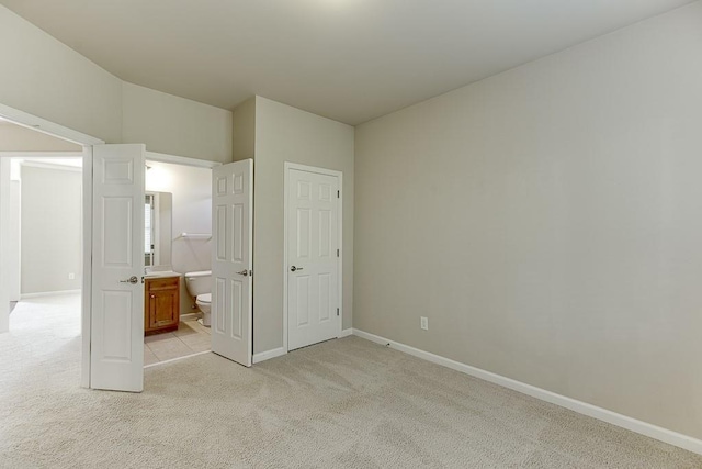 unfurnished bedroom featuring light colored carpet and ensuite bathroom