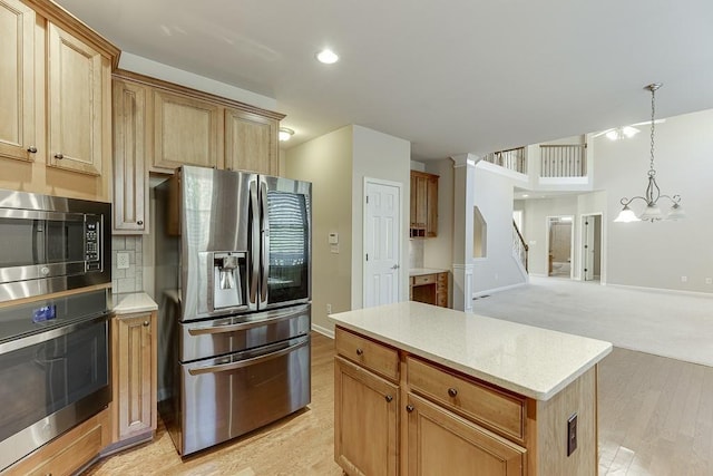 kitchen with a center island, hanging light fixtures, an inviting chandelier, light colored carpet, and appliances with stainless steel finishes