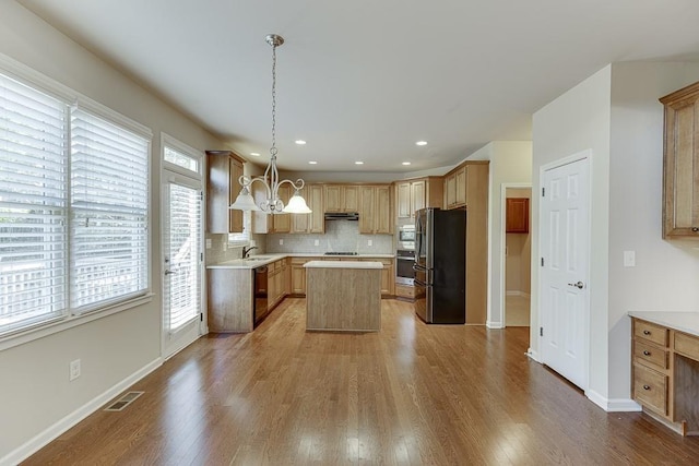 kitchen featuring a center island, stainless steel appliances, decorative light fixtures, and wood-type flooring