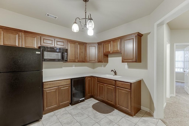 kitchen with sink, hanging light fixtures, beverage cooler, an inviting chandelier, and black appliances