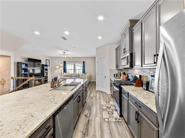 kitchen with a sink, light wood-style floors, appliances with stainless steel finishes, gray cabinetry, and visible vents