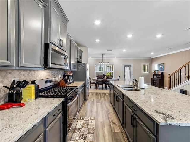 kitchen with crown molding, appliances with stainless steel finishes, gray cabinets, and a sink