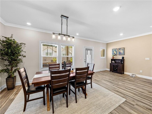 dining space featuring light wood finished floors, crown molding, and baseboards
