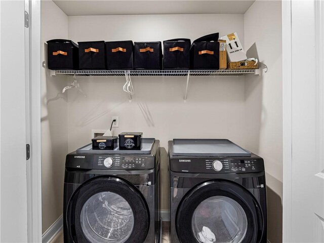 clothes washing area with baseboards, washer and clothes dryer, and laundry area