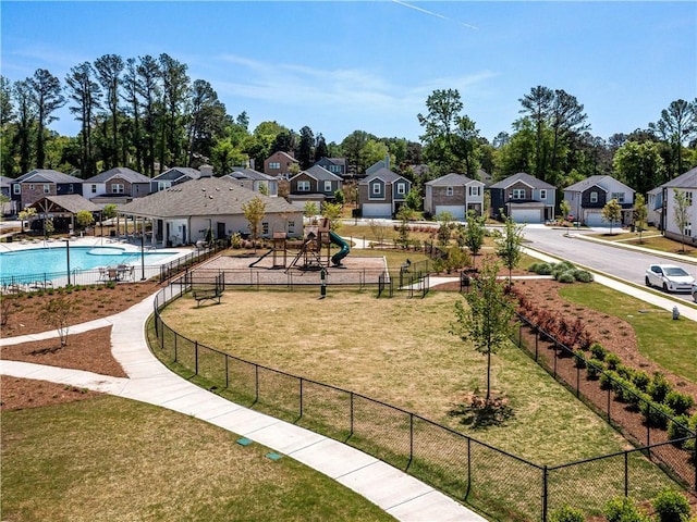 exterior space with a residential view, a swimming pool, a lawn, and fence