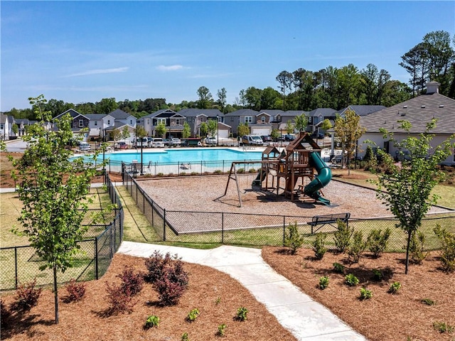 community pool with fence, playground community, and a residential view