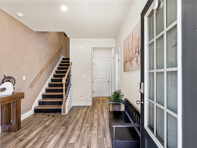 foyer featuring baseboards, stairs, and wood finished floors