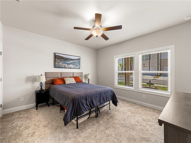 bedroom with a ceiling fan, baseboards, and light carpet