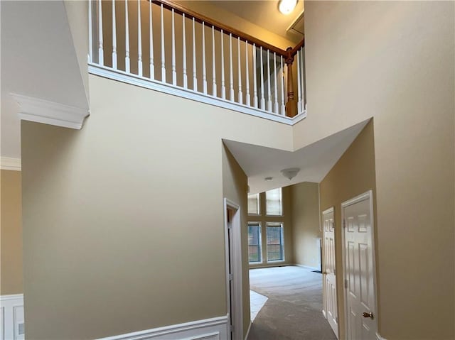 hall with a high ceiling, carpet flooring, and baseboards