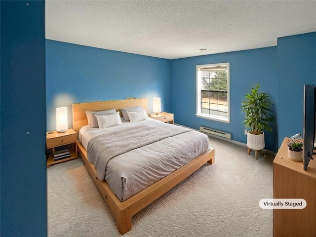 carpeted bedroom featuring a baseboard heating unit and a textured ceiling