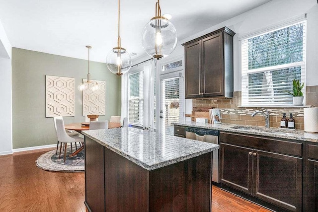 kitchen featuring dark brown cabinetry, sink, light stone counters, light hardwood / wood-style flooring, and a kitchen island