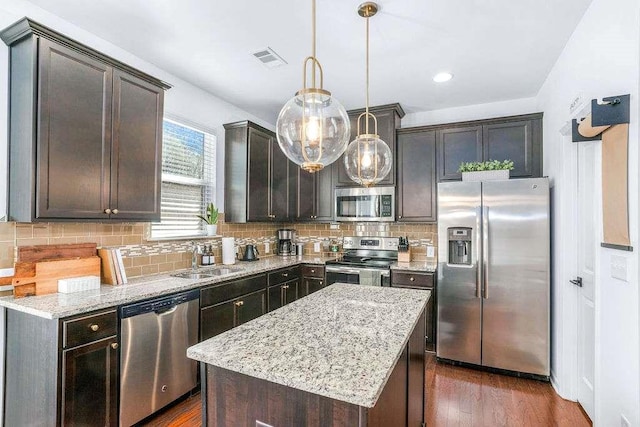 kitchen with a kitchen island, appliances with stainless steel finishes, sink, hanging light fixtures, and dark brown cabinets