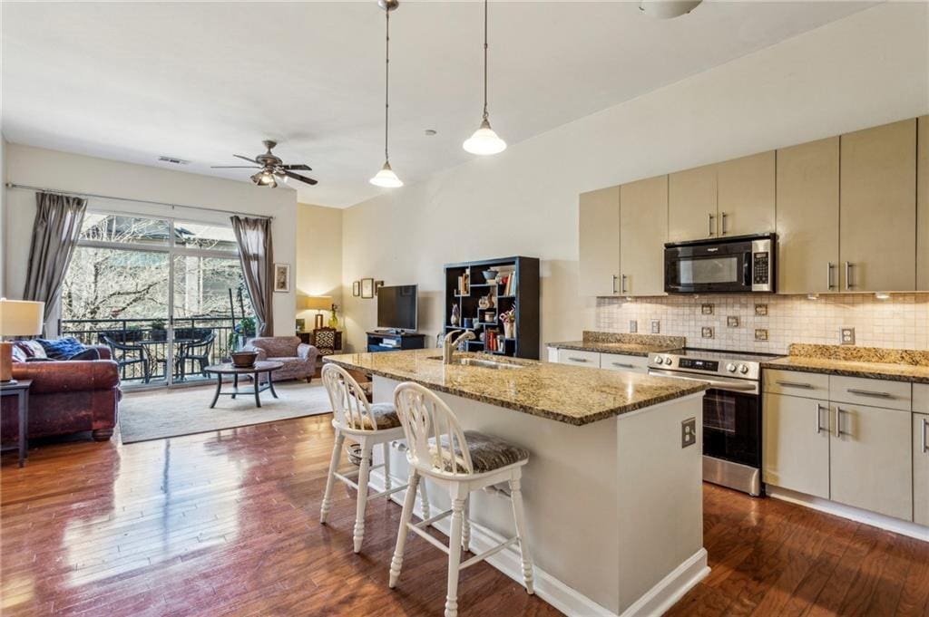 kitchen featuring stainless steel appliances, sink, ceiling fan, decorative backsplash, and light stone countertops