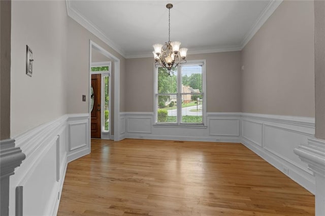3642 Fowler Rdg, Douglasville, GA 30135 - unfurnished dining area featuring a chandelier, ornamental molding, a wainscoted wall, and light wood finished floors