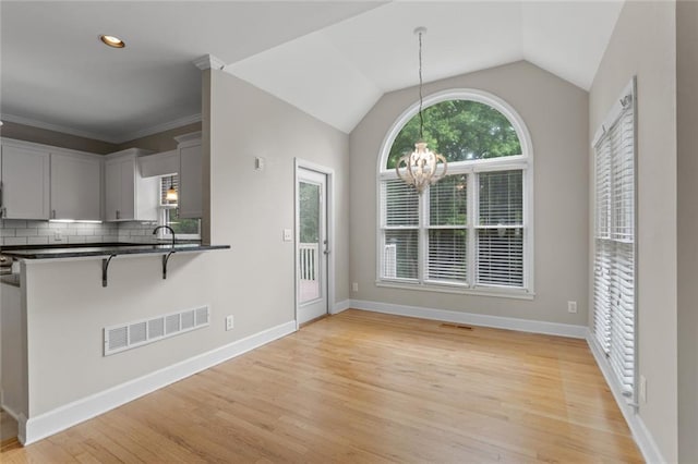 3642 Fowler Rdg, Douglasville, GA 30135 - kitchen with a breakfast bar area, dark countertops, a chandelier, light wood-style flooring, and backsplash