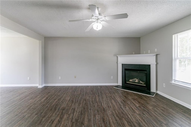 256 Turnstone Rd, Stockbridge, GA 30281 - unfurnished living room featuring dark wood-style flooring, a glass covered fireplace, ceiling fan, a textured ceiling, and baseboards