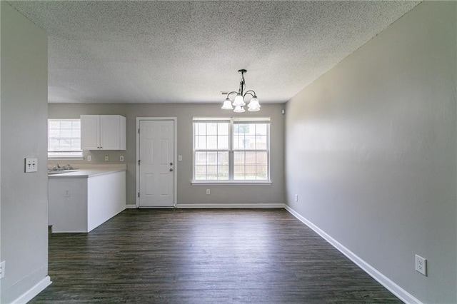 256 Turnstone Rd, Stockbridge, GA 30281 - unfurnished dining area featuring a chandelier, dark wood finished floors, a textured ceiling, and baseboards