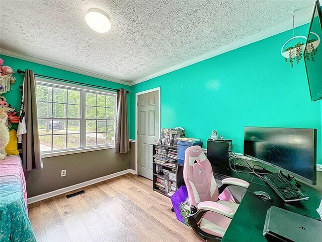 home office with a textured ceiling, visible vents, crown molding, wood finished floors, and baseboards
