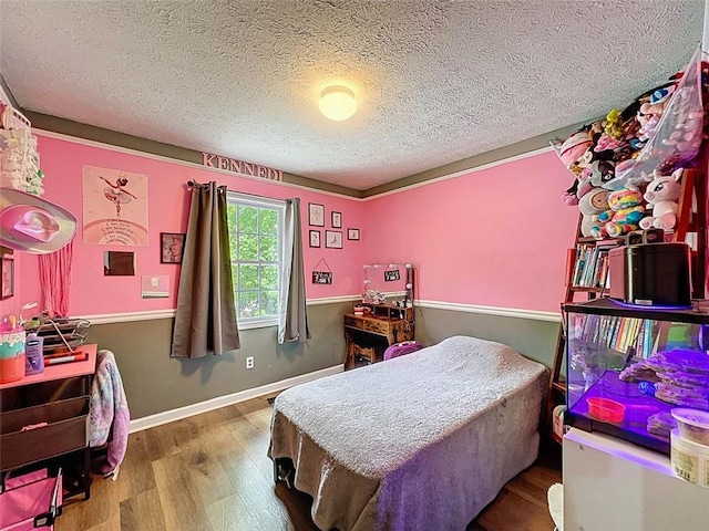 bedroom with baseboards, a textured ceiling, and wood finished floors