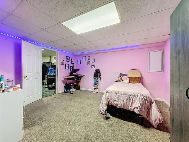 carpeted bedroom featuring baseboards and a drop ceiling