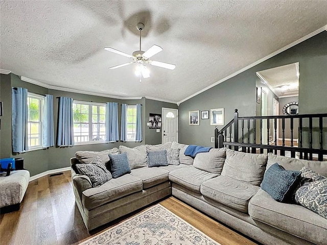 living area with a textured ceiling, ceiling fan, ornamental molding, and wood finished floors