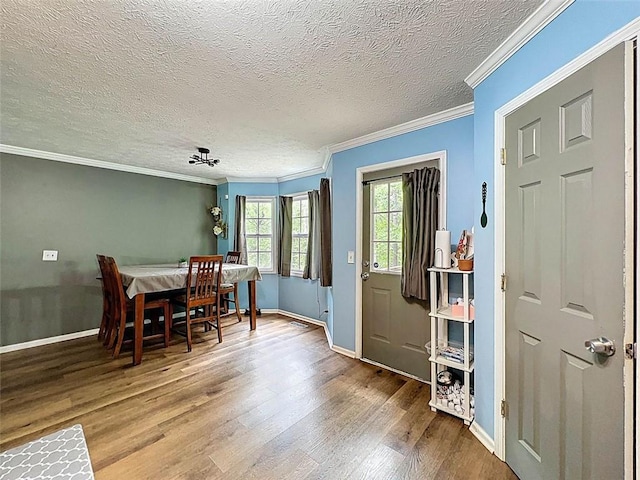 dining area with baseboards, ornamental molding, a textured ceiling, and wood finished floors