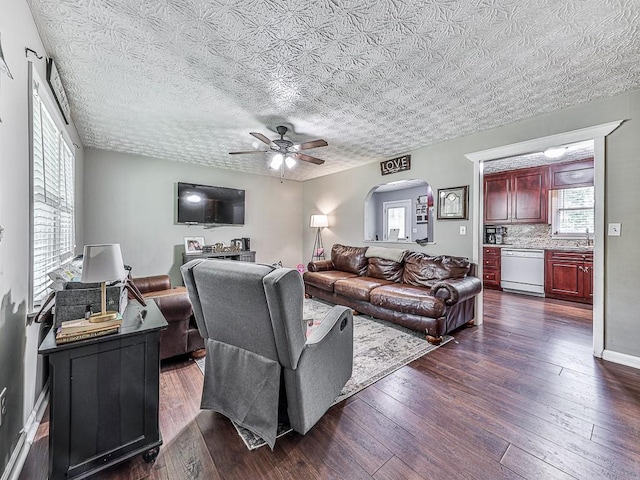 living room featuring ceiling fan, dark hardwood / wood-style flooring, and a textured ceiling