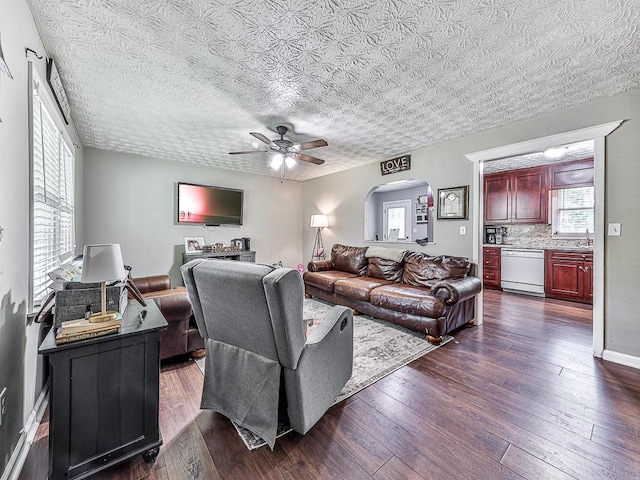 living room with ceiling fan, dark hardwood / wood-style flooring, and a textured ceiling