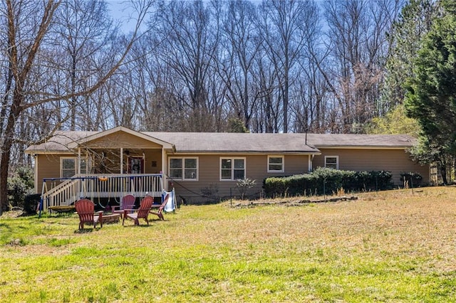 back of property featuring a lawn, a fire pit, and a deck