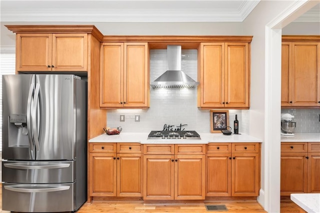 kitchen with visible vents, wall chimney range hood, stainless steel appliances, light wood-style floors, and light countertops