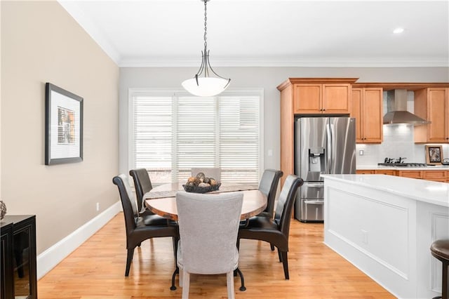 dining space featuring crown molding, light wood-type flooring, and baseboards