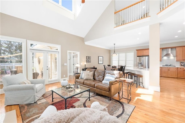 living area with baseboards, ornamental molding, french doors, a high ceiling, and light wood-style floors