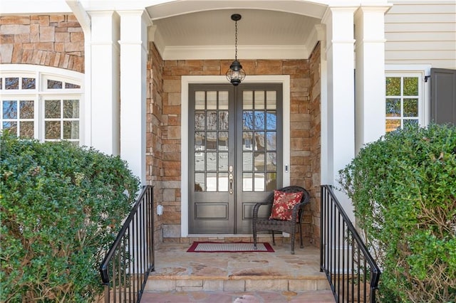 property entrance with french doors, stone siding, and a porch