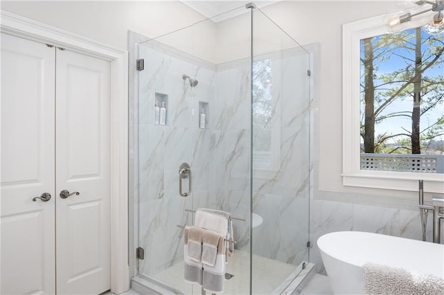 full bathroom featuring a freestanding tub and a marble finish shower