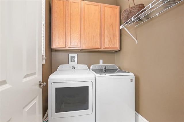 clothes washing area with washer and dryer and cabinet space