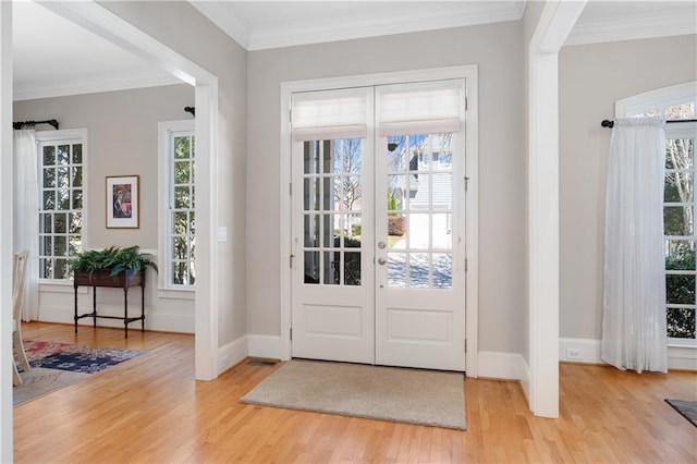 entrance foyer featuring a wealth of natural light, ornamental molding, and wood finished floors