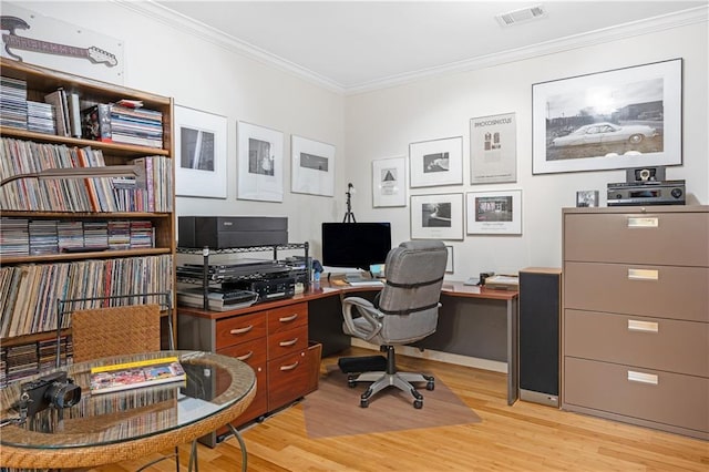 office space with crown molding, light wood-style floors, and visible vents