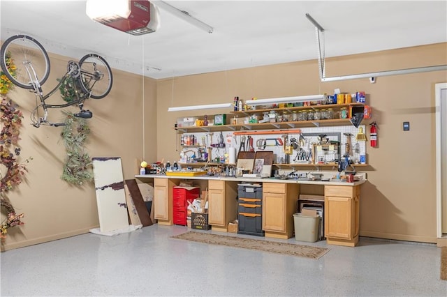 garage with a workshop area, a garage door opener, and baseboards